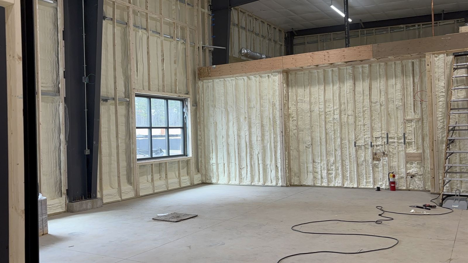Wide view of a large steel building with the interior fully insulated in spray foam.