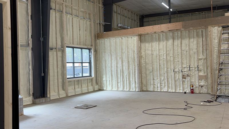 Large steel building interior insulated with foam, with windows and framed openings left clean.