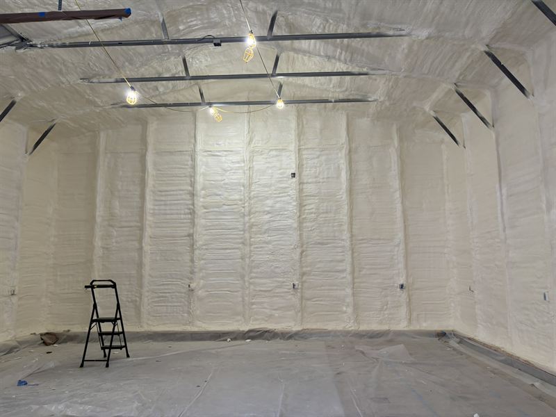 Completed metal garage insulation with lights installed and the floor swept clean.