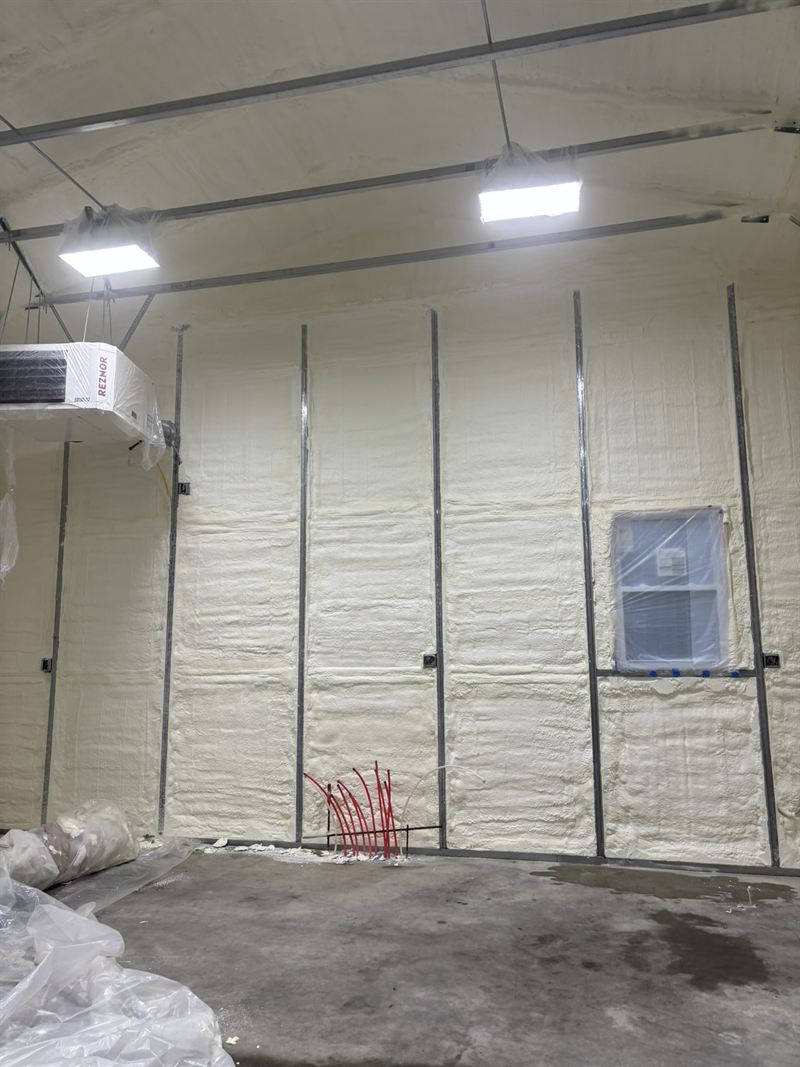 Insulated metal garage interior with overhead door and lighting installed.