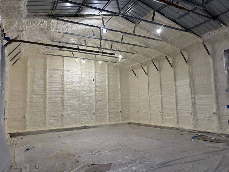 Metal garage interior with walls and ceiling coated in bright white closed-cell spray foam.
