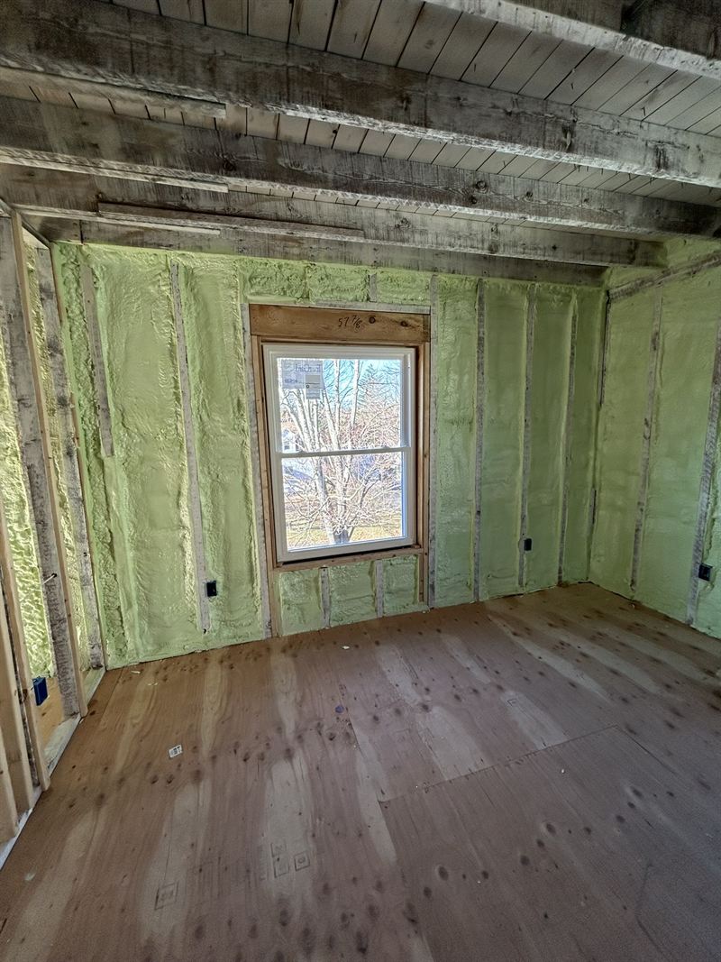 Remodelled room with green open-cell foam filling every stud bay around a window.