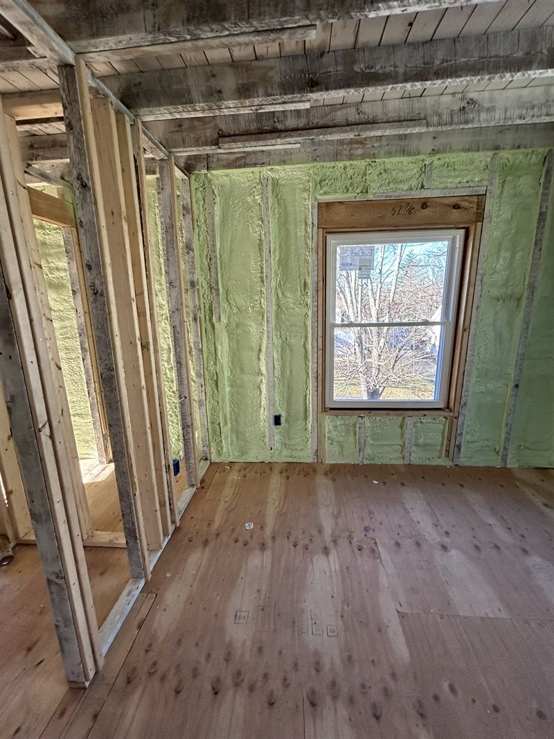 Bedroom in a remodel with every stud bay filled with open-cell spray foam, trimmed flush to the framing.