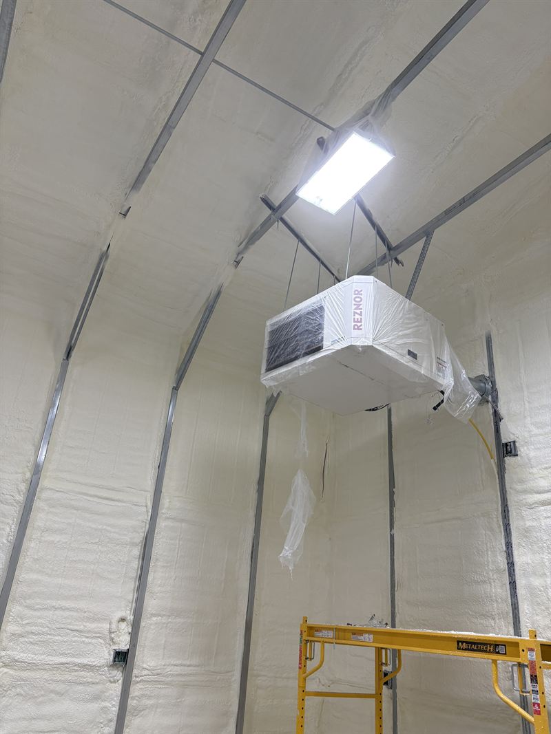 Arched quonset-style building with the interior arch fully insulated and a wall unit installed.