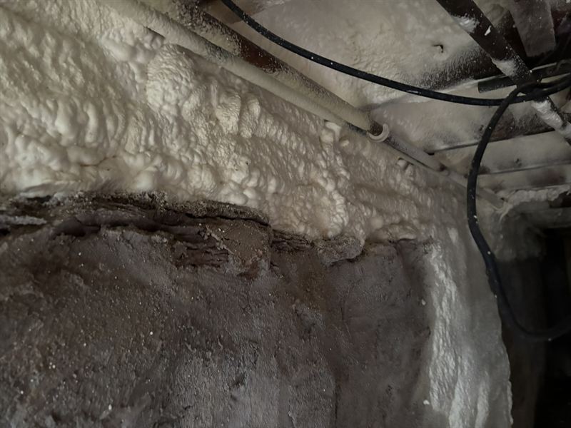 Close-up of closed-cell foam sealing a basement rim joist and sill plate.