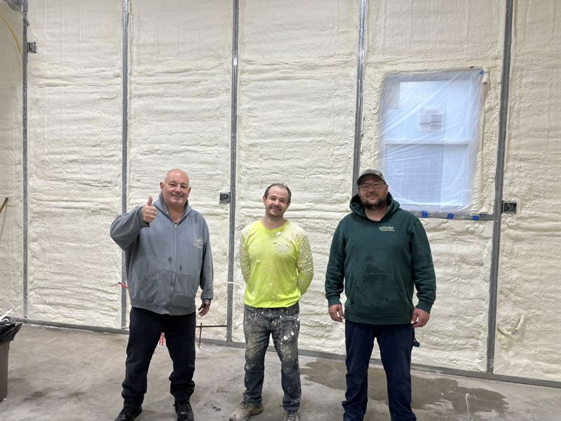 Three members of the San Diego Spray Foam crew standing in a finished, fully insulated metal building.
